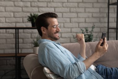 Genç adam kanepede uzanmış, akıllı telefondan güzel bir selfie çekiyor.