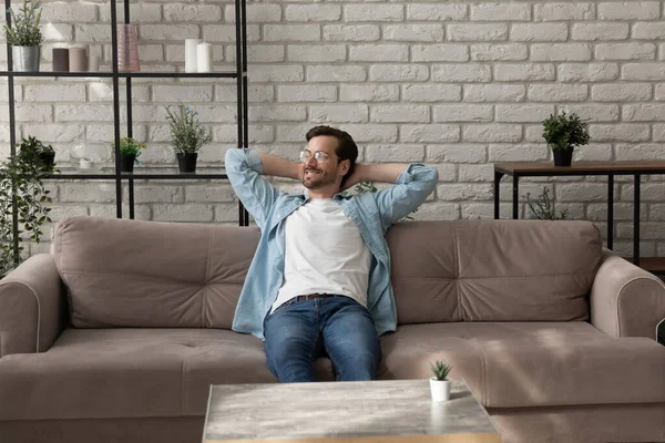 Tranquilo hombre milenario relajándose en cómodo sofá después de terminar el trabajo — Foto de Stock