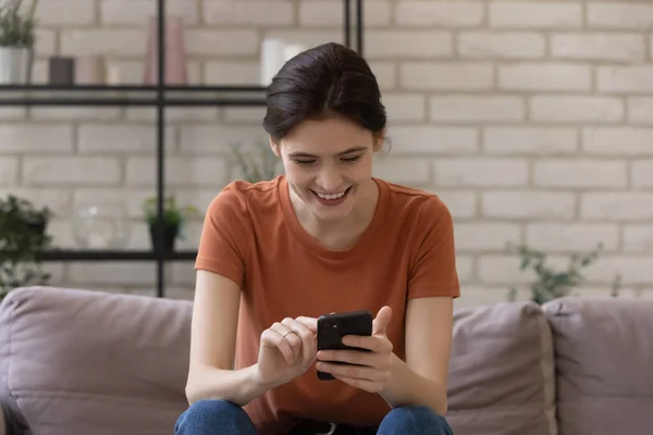 Joyeux jeune femme axée sur la messagerie à l'écran du téléphone avec des amis — Photo