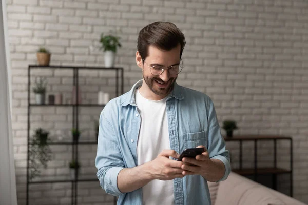 Hoopvolle jonge man staat binnen betrokken bij het kiezen van telefoonnummer — Stockfoto