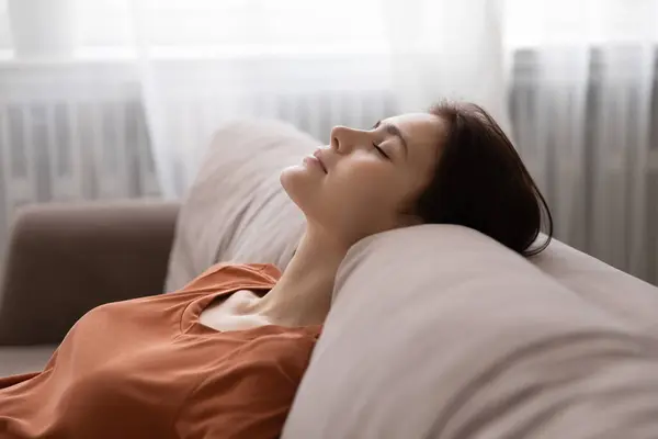 Serene vrouw leunend terug op bank dromen met gesloten ogen — Stockfoto