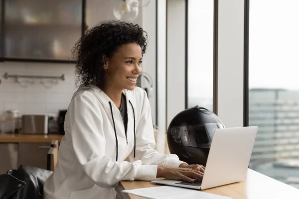 Leende biracial kvinna biker arbete på laptop hemma — Stockfoto