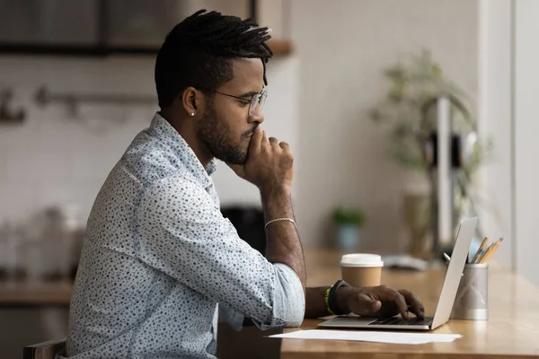 Hombre biracial pensativo mirar la pantalla del ordenador portátil de trabajo en línea — Foto de Stock