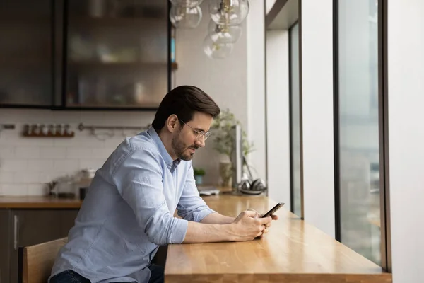 Giovanotto guarda lo schermo dello smartphone messaggiare online — Foto Stock