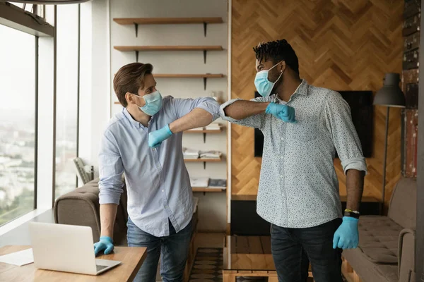 Усміхнені багаторасові чоловічі привітання в офісі під час пандемії — стокове фото