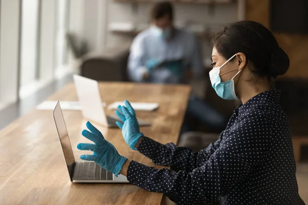 Trabalhadora no trabalho de máscara médica no laptop — Fotografia de Stock