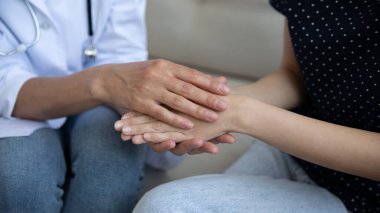 Yardımsever kadın doktor elleri hasta kadının avuçlarını tutuyor.