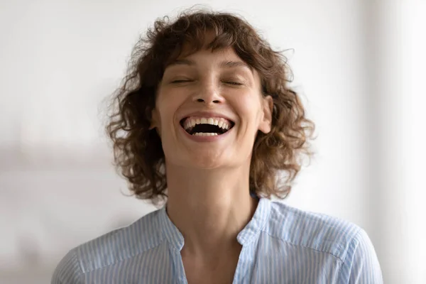 Беззаботная позитивная молодая женщина смеется вслух с закрытыми глазами — стоковое фото