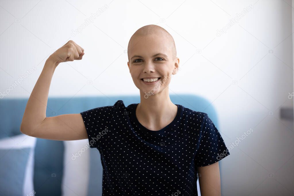 Self confident woman combating against oncology demonstrate muscles strength symbol