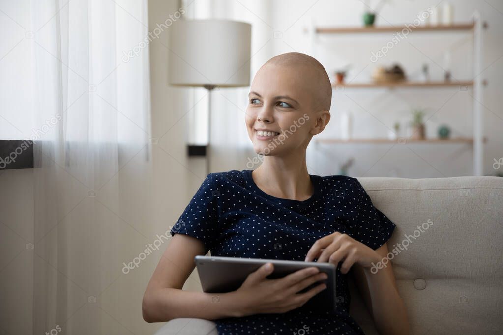 Optimistic female cancer patient rest on couch with digital tablet