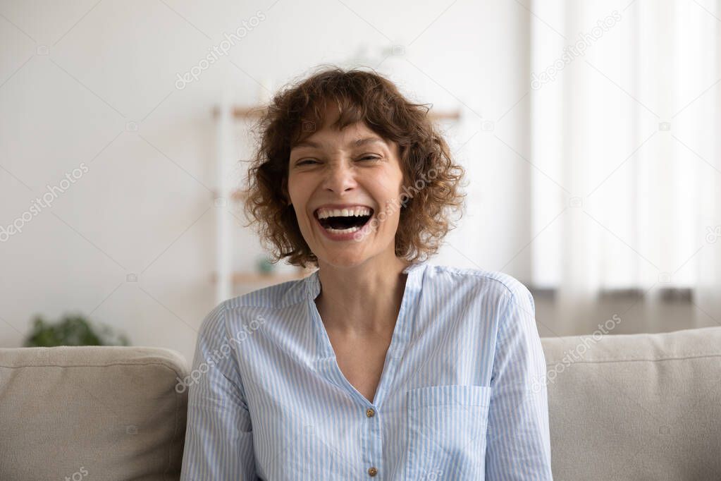 Overjoyed young female laughing on cute joke demonstrating perfect teeth
