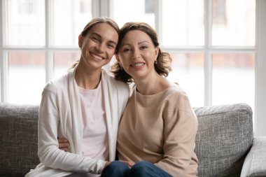 Orta yaşlı anne ve yetişkin kız gibi gülümseyen bir portre.