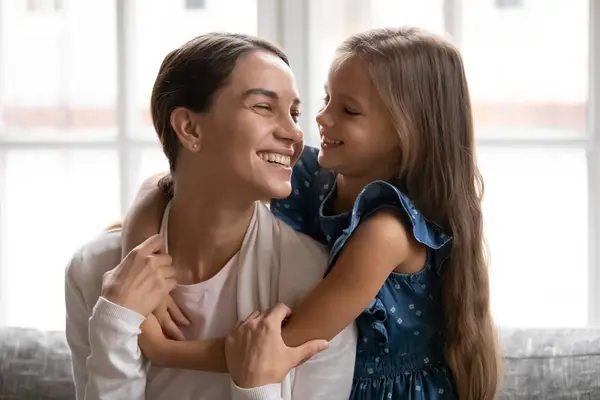 Крупным планом улыбающаяся маленькая девочка обнимает молодую красивую мать — стоковое фото