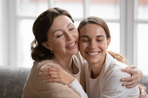 Close up gelukkig middelbare leeftijd moeder en volwassen dochter knuffelen — Stockfoto