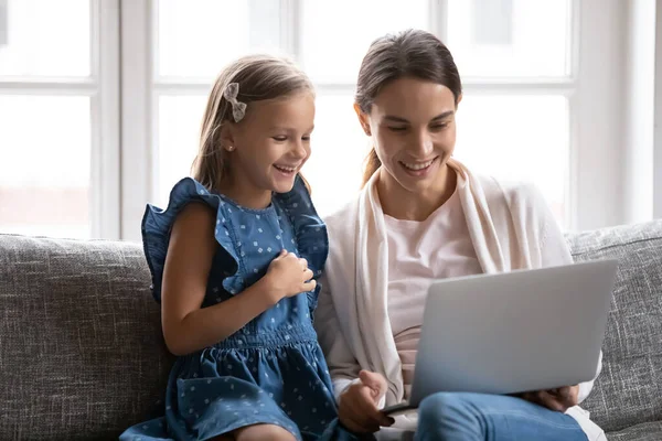 Cerca de niña muy alegre con la madre usando el ordenador portátil juntos — Foto de Stock