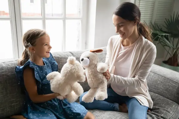 Закройте мать и маленькую девочку, играющих с пушистыми игрушками — стоковое фото