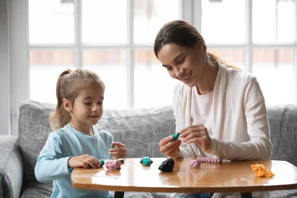Leende mor och liten dotter leker med färgglada deg — Stockfoto