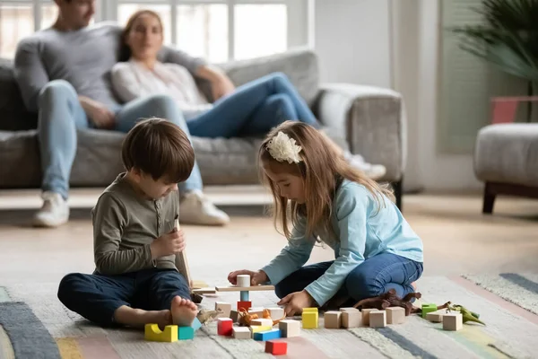 Gros plan enfants d'âge préscolaire jouant ensemble à des jouets pendant que les parents se détendent — Photo