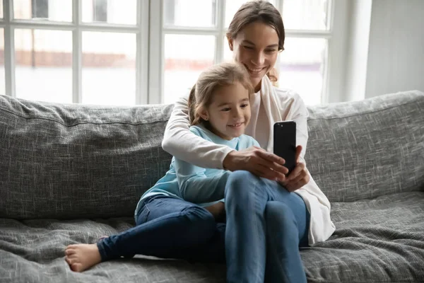 Крупним планом мати і маленька дочка розважаються з телефоном — стокове фото
