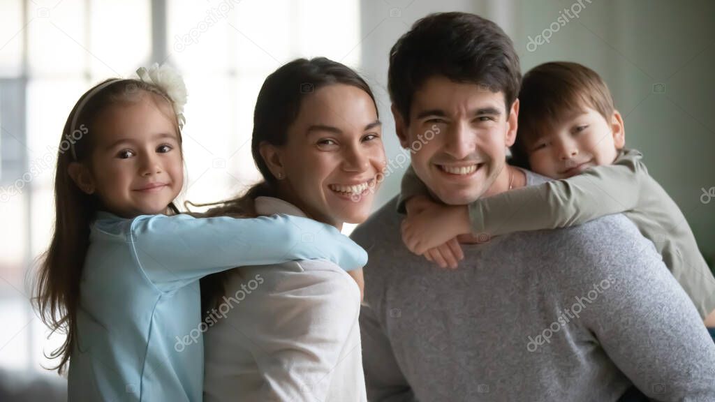 Head shot portrait smiling mother and father piggy backing kids