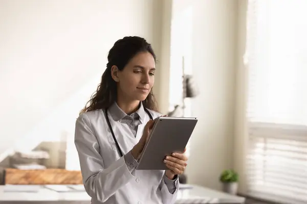 Жінка-лікар працює на сучасному планшеті в клініці — стокове фото