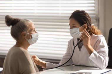 Bayan doktor, yaşlı hastanın kalbini dinle.