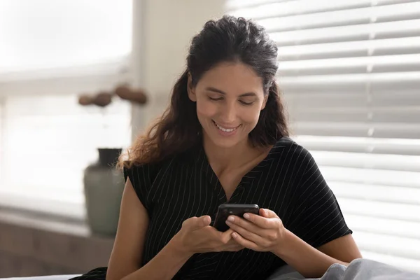 Mujer sonriente mira la mensajería de la pantalla del teléfono celular — Foto de Stock