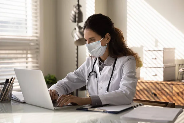 Médico femenino en el trabajo de máscara facial en el ordenador — Foto de Stock