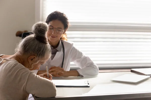 Страхование пожилых женщин с врачом в клинике — стоковое фото