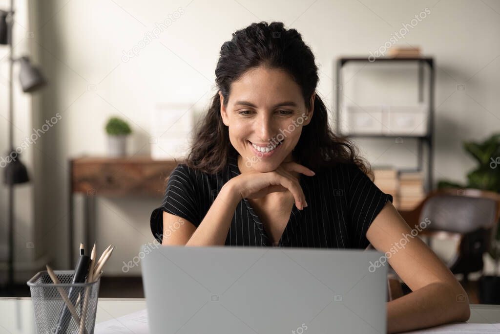 Smiling young woman work on computer at home