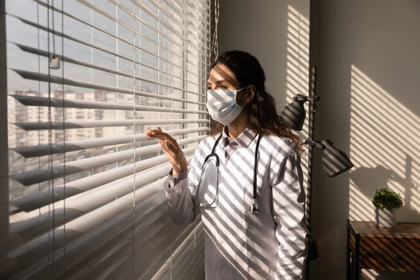 Médico mujer en la máscara de la cara mirada en la distancia soñando — Foto de Stock