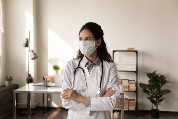 Female GP in facial mask look in distance thinking — Stock Photo, Image
