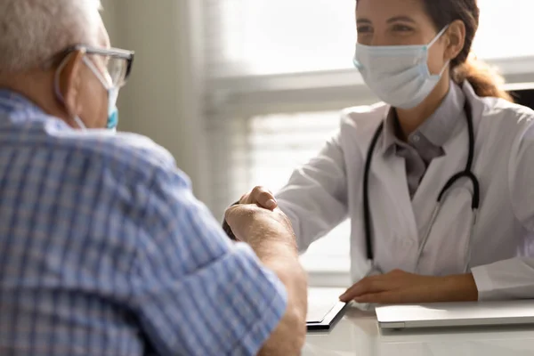 Hastanede doktor ve yaşlı hastaların el sıkışmalarını kapat. — Stok fotoğraf