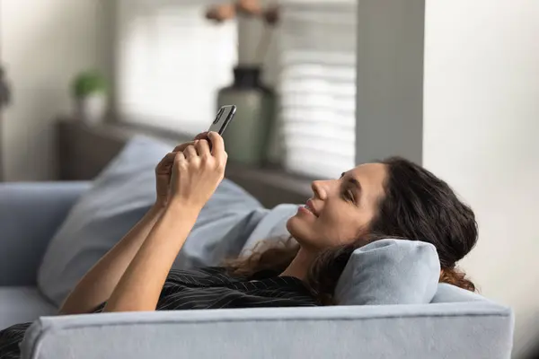 Mujer feliz relajarse en el sofá usando gadget smartphone — Foto de Stock