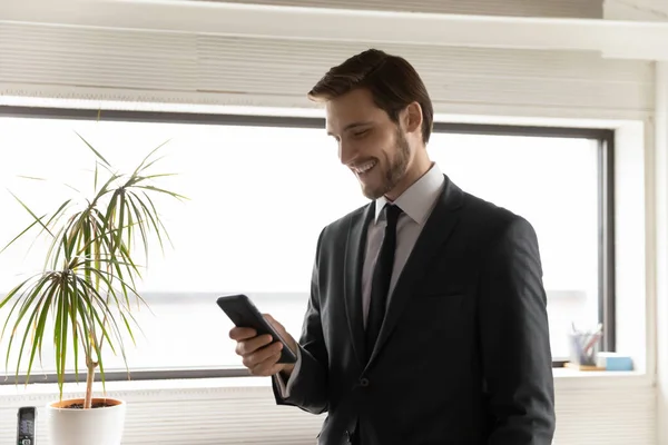 Smiling businessman use smartphone texting in office — Stock Photo, Image