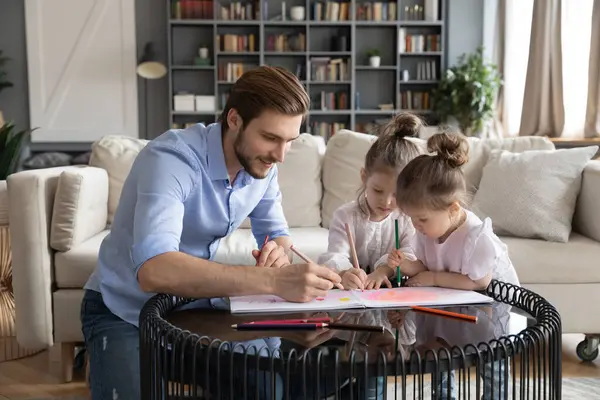 Liebenswerter Papa zeichnet mit zwei kleinen Töchtern — Stockfoto