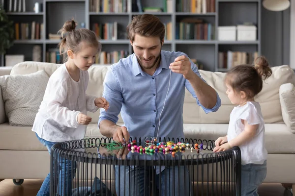 Caring dad make bracelets with little daughters — Stock Photo, Image