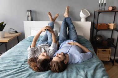 Mutlu çift yatakta birlikte akıllı telefon kullanıyor.