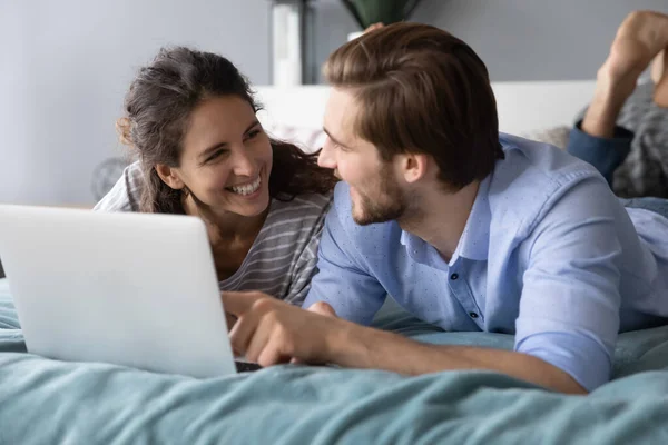 Mutlu çift yatakta birlikte bilgisayar kullanarak rahatlıyor. — Stok fotoğraf