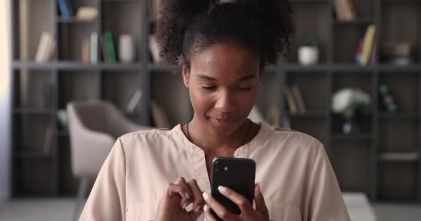 Mulher africana segurando smartphone moderno desfrutar de bate-papo remoto com amigo — Vídeo de Stock