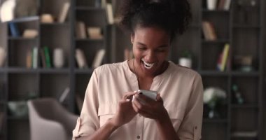 Gülümseyen neşeli Afrikalı kadın akıllı telefon kullanarak sohbet etmekten zevk alıyor.