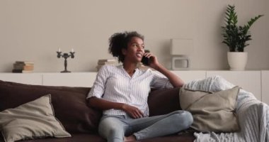 Kanepede dinlenen Afrikalı kadın telefonda arkadaşlarıyla konuşuyor.