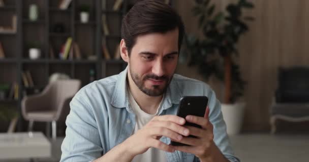 Hombre sentarse en interiores utilizando el teléfono móvil disfrutar del tiempo en Internet — Vídeo de stock