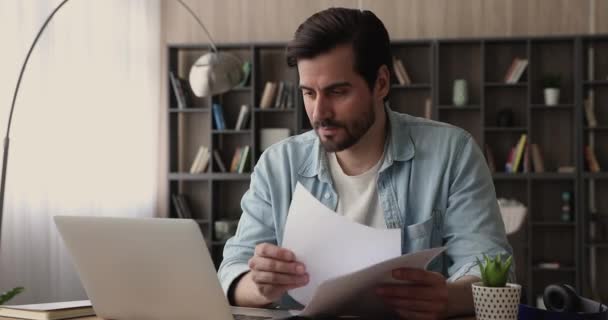 Homme travaillant avec des documents et un ordinateur portable au bureau — Video