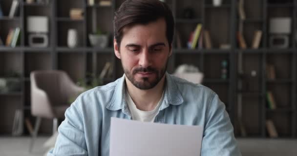 Un om de afaceri nerăbdător care citește vești proaste într-o scrisoare așezată la locul de muncă — Videoclip de stoc