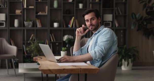 Exitoso sonriente hombre de negocios sentarse en el lugar de trabajo mirando a la cámara — Vídeos de Stock