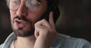 Gözlüklü genç telefonda konuşuyor, yakın plan portresi.
