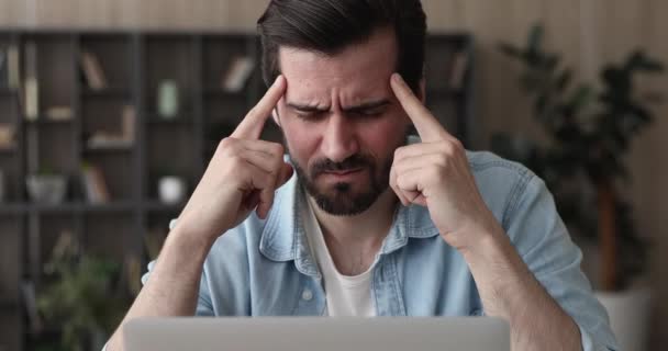 Hombre sentarse en interiores ojos cerrados frotar templos que sufren de dolor de cabeza — Vídeos de Stock