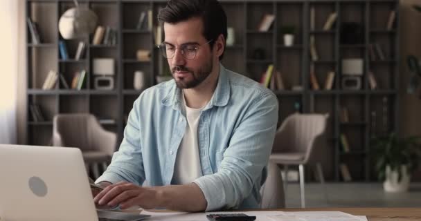 Man sit at desk calculate costs using calculator and laptop — Stock Video