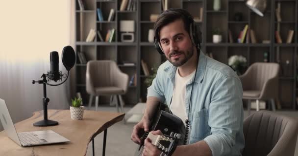 Guitarrista usar fones de ouvido segurando uma guitarra sorrindo olhando para a câmera — Vídeo de Stock